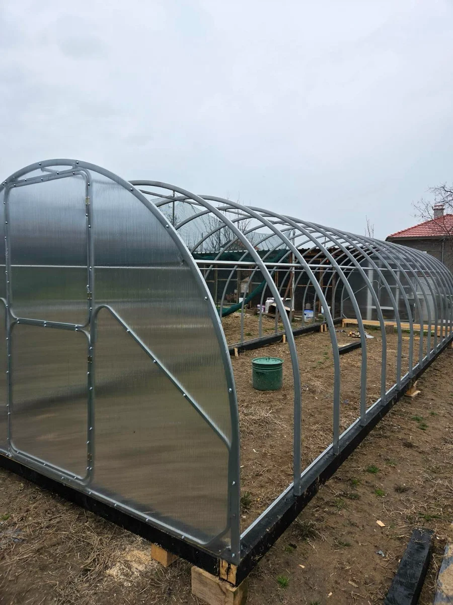 Partially assembled greenhouse showing the galvanized-steel frame and fitted end panels