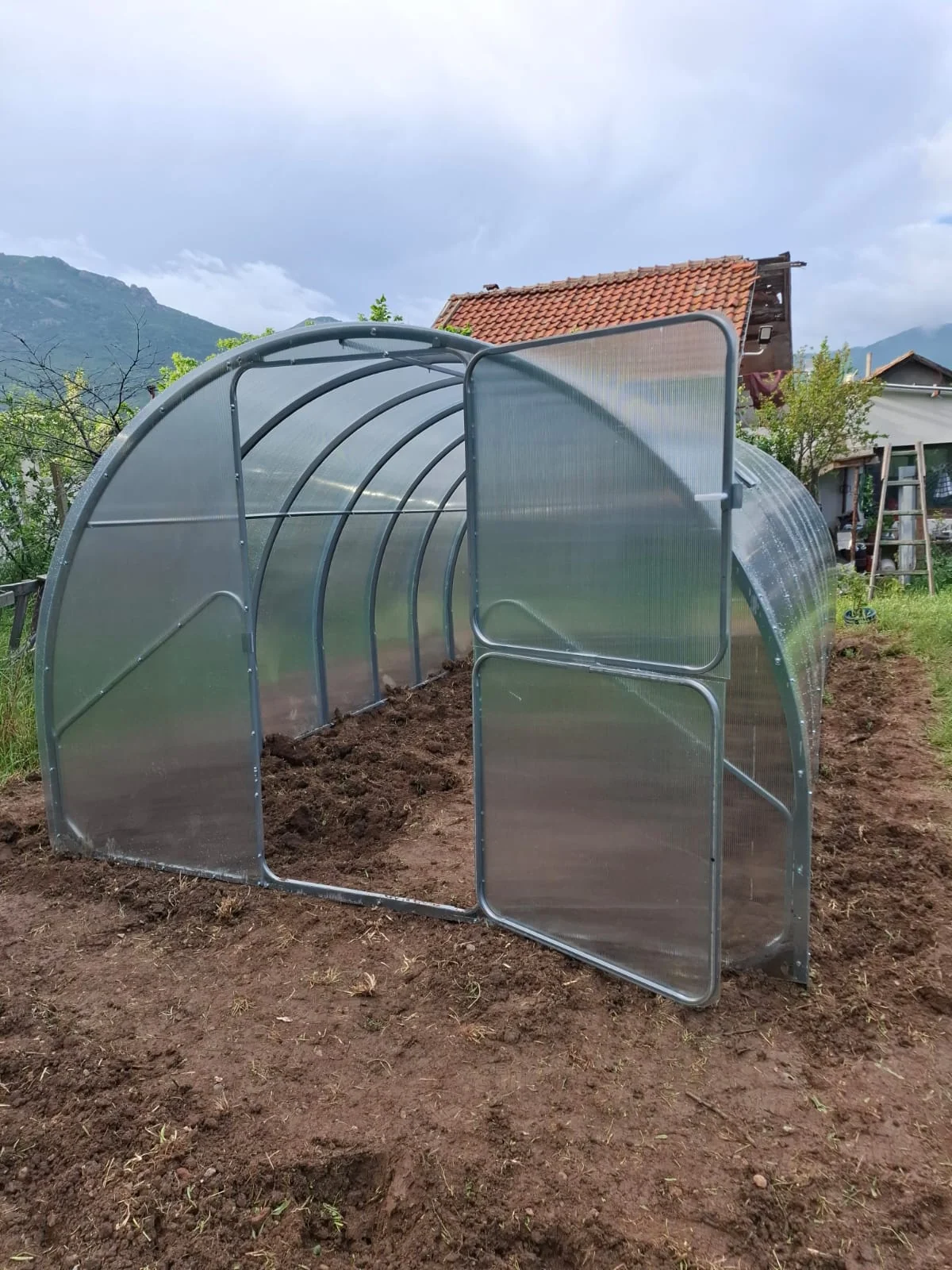 Open outward-swinging door and interior access of an installed Barcelona greenhouse